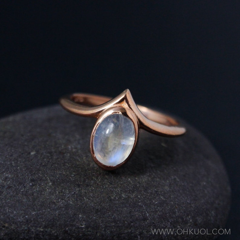 Puede incluir: Un anillo de oro rosa con un dise&ntilde;o delicado y puntiagudo y una piedra ovalada de piedra lunar.