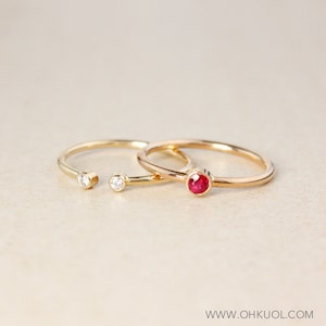Peut inclure: Deux bagues en or avec des pierres précieuses. Une bague a une pierre rouge et l'autre bague a deux pierres claires.