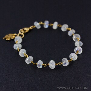 May include: A delicate gold chain bracelet with a small leaf charm and white moonstone beads.