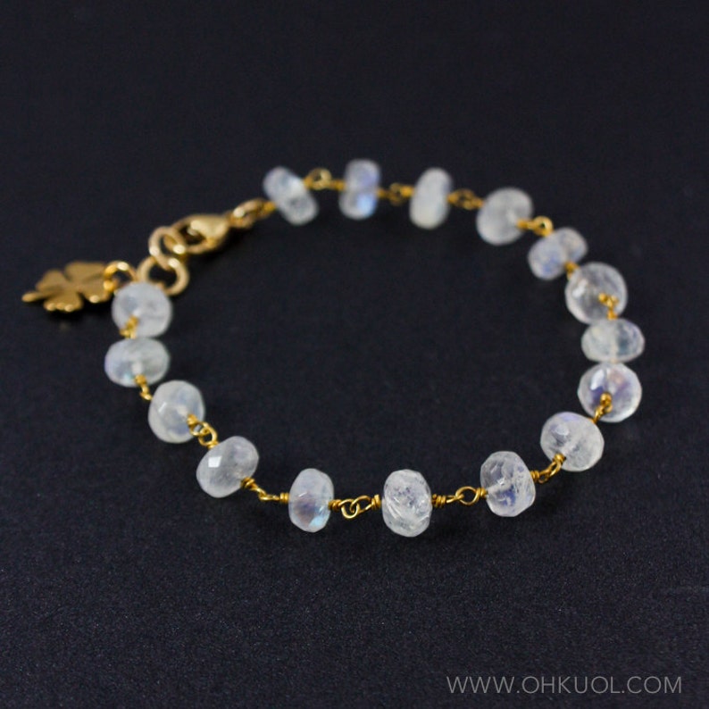 May include: A delicate gold chain bracelet with a small leaf charm and white moonstone beads.