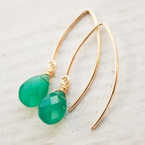 May include: A pair of gold earrings with green gemstone drops. The earrings are made with a simple wire design and feature a teardrop-shaped gemstone.