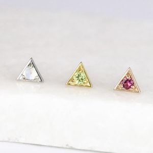 May include: Three triangle-shaped earrings with a single gemstone in the centre of each. The earrings are silver, gold, and rose gold. The gemstones are white, green, and pink.