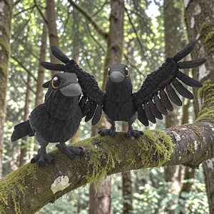 Puede incluir: Dos figuras de cuervos negros con alas detalladas y ojos amarillos posadas en una rama cubierta de musgo. Un cuervo tiene las alas extendidas. El fondo presenta una escena borrosa de un bosque con árboles altos.