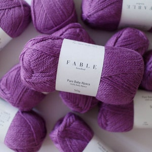 May include: Purple balls of yarn labelled "FABLE handknit Pure Baby Alpaca 100% Baby Alpaca 50g"