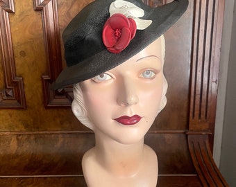 Elegant mid 1930s “Ydelle” Viennese hat in black straw with leather flower trim in red and white. Small/medium up to 22” head.