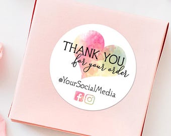 May include: Round sticker with a watercolor heart design in shades of pink, yellow, and green. The sticker says "Thank You for your order" and includes the text "@YourSocialMedia" with icons for Facebook and Instagram.