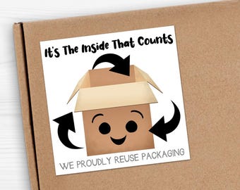 May include: A brown cardboard box with a white sticker. The sticker features a cartoon box with a smiling face, surrounded by recycling arrows. Text on the sticker reads "It's The Inside That Counts" and "WE PROUDLY REUSE PACKAGING".