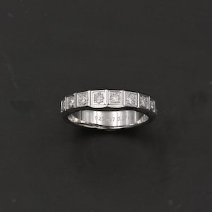 Op de afbeelding: Een zilveren bandring met een rij kleine vierkante diamanten die in de band zijn gezet. De ring is gegraveerd met "925 0.7 0.276".