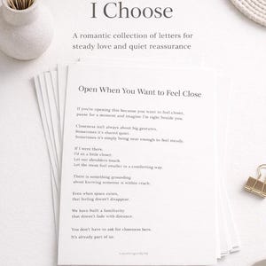 May include: A stack of white paper with the text "Open When You Want to Feel Close" and other romantic text. The title "For the One I Choose" is at the top. A small vase with dried flowers and a gold paper clip are also visible.