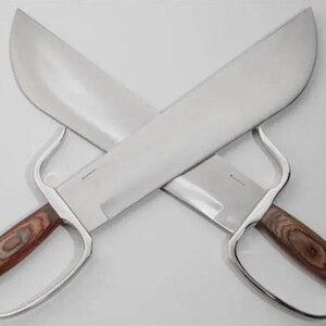 May include: Two crossed, large, silver-bladed knives with wooden handles. The blades are wide and curved, and the handles feature a finger guard. The knives are displayed against a white background.
