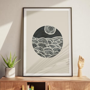 May include: Framed art print with a circular black and white illustration. The artwork shows stylized waves and a sun or moon with a spiral design. The print is set against a neutral background and framed in black, ideal for home decor, measuring approximately 50 x 70 cm.