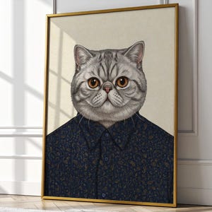 May include: Framed art print featuring a detailed illustration of a gray cat with striking orange eyes. The cat is depicted wearing a navy blue button-down shirt with a gold paisley pattern. The artwork is set in a gold frame.