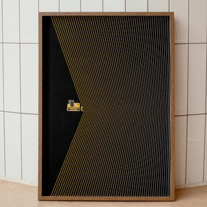 May include: A framed art print featuring a yellow bulldozer icon on a black background. The design incorporates yellow and white parallel lines, creating a visual effect. The frame is a natural wood color.