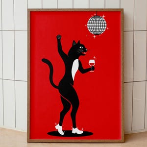May include: A framed art print featuring a black cat dancing with a glass of red wine, set against a vibrant red background. The cat is wearing white shoes and has a white patch on its chest. A disco ball hangs above.