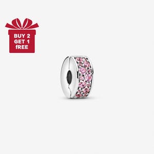 May include: A silver charm with a band of pink gemstones. The charm has a clasp design and a dark centre. The image also includes a red gift box with the text "BUY 2 GET 1 FREE".