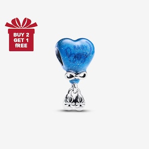 May include: A blue heart-shaped charm with the word "Baby" written on it, attached to a silver bow and a pair of silver ballet slippers. The charm has a glittery texture.