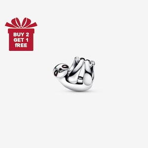 Op de afbeelding: Een zilverkleurige bedel in de vorm van een luiaard, ondersteboven hangend. De luiaard heeft donkerbruine ogen en hangt aan zijn armen en benen. Een rode geschenkdoos met de tekst "BUY 2 GET 1 FREE" staat in de linkerbovenhoek.
