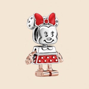 Pode incluir: Um charm da Minnie Mouse com cabe&ccedil;a prateada, la&ccedil;o vermelho e vestido vermelho com bolinhas brancas. O charm tem bra&ccedil;os e pernas em ouro rosa. Um item de colecionador. O charm foi projetado para ser adicionado a uma pulseira ou colar.