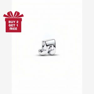 May include: A shiny silver charm in the shape of a musical eighth note. The charm is highly polished and reflects light. A red gift box with the text "BUY 2 GET 1 FREE" is in the upper left corner.