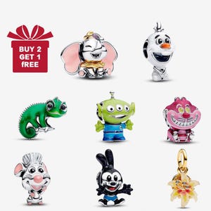 Puede incluir: Colección de abalorios de personajes, incluyendo Dumbo, Olaf, un camaleón verde, un extraterrestre, el Gato de Cheshire, un ratón chef, Oswald el Conejo Afortunado y una flor. También hay una caja de regalo roja con el texto "BUY 2 GET 1 FREE".