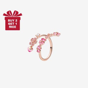 Puede incluir: Un anillo de oro rosa con un diseño floral. El anillo presenta flores rosas y una pequeña piedra transparente. El anillo tiene una apariencia delicada y elegante. La imagen también incluye una caja de regalo roja con el texto "COMPRA 2 Y LLÉVATE 1 GRATIS".