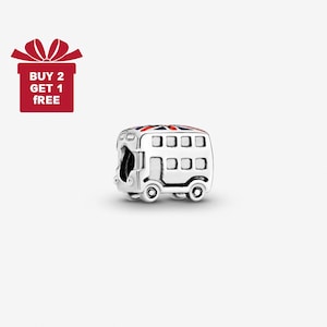 May include: A silver charm depicting a double-decker bus, featuring a Union Jack design on the roof. The bus has rectangular windows and circular wheels. A red gift box with the text "BUY 2 GET 1 FREE" is in the upper left corner.