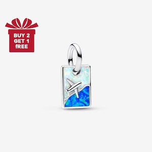 Può includere: Un charm in argento con un ciondolo rettangolare raffigurante un aereo sopra onde blu e bianche. Il charm ha un anello per attaccarlo a un braccialetto o una collana. L'immagine include anche una confezione regalo rossa con la scritta "BUY 2 GET 1 FREE".
