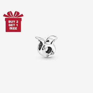 May include: A silver-colored charm with a Taurus zodiac symbol design. The charm features a bull's head with small, clear gemstones. The image also includes a red gift box with the text "BUY 2 GET 1 FREE".