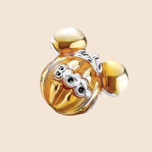 May include: A gold-colored charm with a Mickey Mouse head design. The charm features a ribbed body with the word "Boo" in silver lettering and two black accents. The charm has two gold-colored spheres on top.