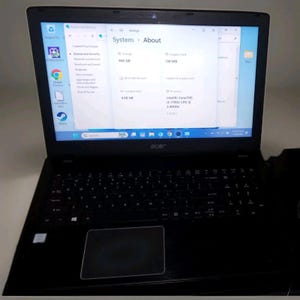 Könnte beinhalten: Ein schwarzer Acer-Laptop mit einem Bildschirm, der das Windows-System-Info-Menü anzeigt. Der Bildschirm zeigt technische Daten wie 466 GB Speicherplatz, 4,00 GB installierten Arbeitsspeicher und einen Intel Core i3-7100U CPU mit 2,40 GHz.