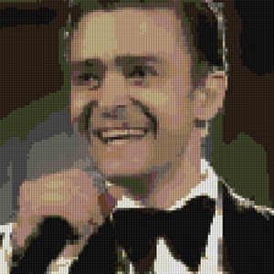 May include: A man wearing a black tuxedo with a white shirt and a black bow tie smiles and adjusts his collar. He has short brown hair and a clean-shaven face.
