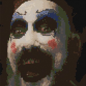 May include: A close-up of a person's face with blue and green makeup, red blush, and a white background. The person has a mustache and a beard.