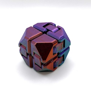 Puede incluir: Un juguete de rompecabezas geométrico multicolor con un brillo metálico. El rompecabezas está compuesto por varias piezas entrelazadas, que muestran tonos de púrpura, rojo y verde azulado. El objeto está sobre un fondo blanco liso.