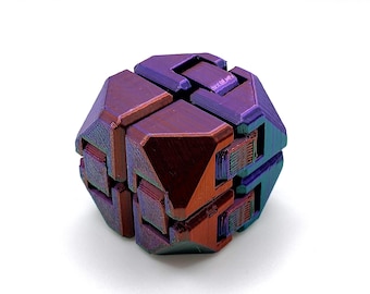 Puede incluir: Un juguete de rompecabezas geométrico multicolor con un brillo metálico. El rompecabezas está compuesto por varias piezas entrelazadas, que muestran tonos de púrpura, rojo y verde azulado. El objeto está sobre un fondo blanco liso.