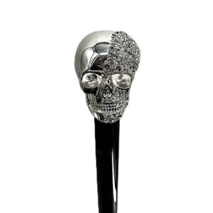 May include: A silver skull cane handle with one half covered in rhinestones. The skull has black eye sockets and a detailed design.