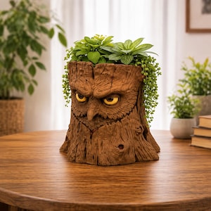 May include: A brown tree stump planter featuring a sculpted owl face with prominent, textured bark details and glowing yellow eyes. The planter is filled with green leafy plants and trailing vines that drape over the sides of the owl's head.