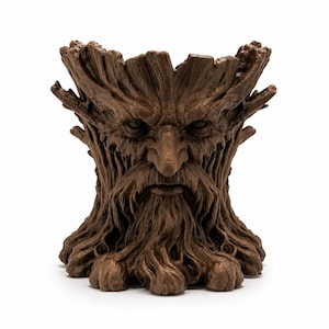 May include: A brown, tree-like sculpture with a face carved into it. The sculpture has a long beard, a prominent nose, and a stern expression. The top of the sculpture is open, creating a bowl-like shape. The base has claw-like feet.