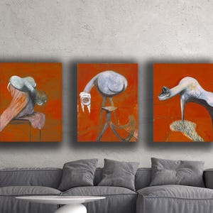 May include: Three abstract paintings with a red-orange background. Each painting features a unique, surreal figure in shades of grey, white, and orange. The artwork is displayed above a grey sofa with a white coffee table.