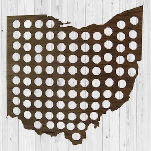 Op de afbeelding: Een houten wanddecoratie in de vorm van de staat Ohio met een patroon van flessenkap-vormige uitsnijdingen. Het hout is donkerbruin en de uitsnijdingen zijn wit.