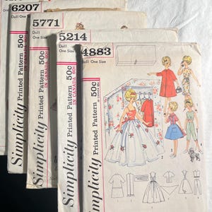 Pode incluir: Cinco padrões de costura vintage Simplicity para bonecas. Os padrões são numerados 6275, 6207, 5771, 5214 e 4883. Cada padrão custa 50 centavos. Os padrões apresentam ilustrações de bonecas vestindo diferentes roupas.