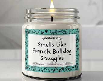 以下が含まれることがあります： 点灯した、銀色の蓋が付いた透明なガラス瓶のキャンドル。「Smells Like French Bulldog Snuggles」と書かれたラベルには、犬をテーマにしたアイコンのターコイズ色のボーダーがあります。キャンドルはシナモンバニラの香りで、プレミアム大豆ワックスで作られています。