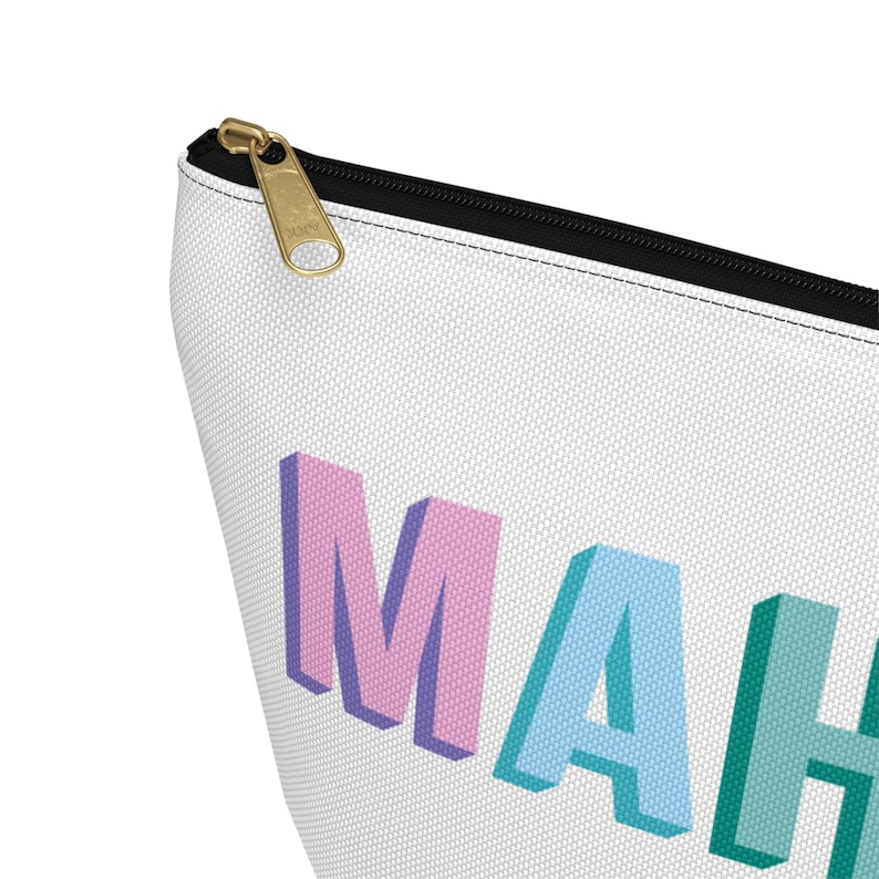 May include: A white zippered pouch featuring the partial text MAH in three-dimensional block letters. The letter M is pink, the letter A is light blue, and the letter H is teal. The pouch has a black zipper track and a gold-toned metal zipper pull.