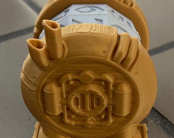 Puede incluir: Un modelo de robot impreso en 3D de color dorado, con un cuerpo redondo, una cabeza giratoria y una base con pequeñas patas. El robot tiene un diseño detallado con tuberías y otras características mecánicas.