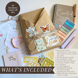 May include: A devotional gift set featuring a brown paper-wrapped package with butterfly and religious stickers, a spiral-bound notebook titled Created, a pen, colorful adhesive tabs, two cross-shaped paper clips, a beaded bracelet, and cards.