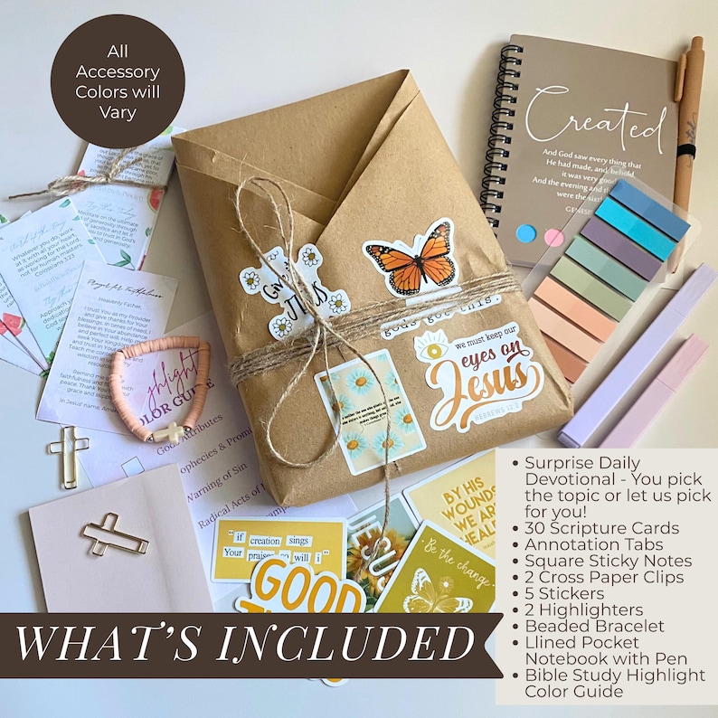 May include: A devotional gift set featuring a brown paper-wrapped package with butterfly and religious stickers, a spiral-bound notebook titled Created, a pen, colorful adhesive tabs, two cross-shaped paper clips, a beaded bracelet, and cards.