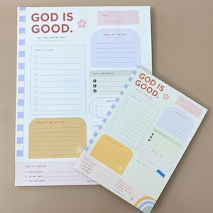 Könnte beinhalten: Zwei Tagesplaner-Blätter mit dem Text GOD IS GOOD. ALL DAY, EVERY DAY. Jedes Blatt enthält Abschnitte für den Tagesplan, den Vers des Tages, die Top-3-Prioritäten, Gebet und Reflexion sowie eine Auswahl mit Kästchen und Linien.
