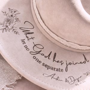 Puede incluir: Sombrero fedora beige claro con un dise&ntilde;o floral y el texto "What God has joined let no one separate Austin & Dayna 04.21.24". El sombrero tiene un ribete decorativo.