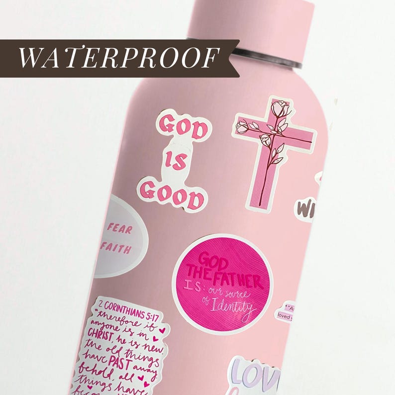 May include: A pink, waterproof water bottle covered in stickers. The stickers feature phrases like "God is Good," a pink cross with floral accents, and other inspirational quotes. The bottle is designed for carrying water or other beverages.