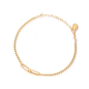 May include: A gold chain bracelet with a rectangular link and a small round charm with the letter "M" on it.