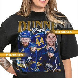 Könnte beinhalten: Schwarzes Unisex-T-Shirt für Erwachsene mit einem Vintage-Design. Es zeigt den Namen "DUNNE" und die Nummer "44". Das Shirt enthält Bilder eines Eishockeyspielers in einem blau-goldenen Trikot. Der Text "Josh Dunne" ist ebenfalls sichtbar.